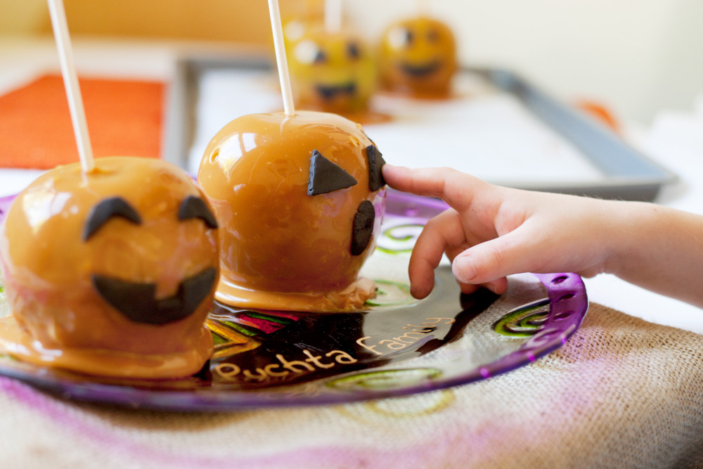 Child adding fondant faces to candy apple