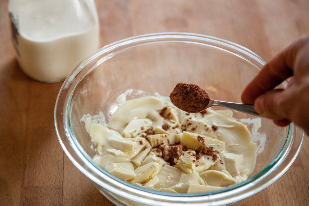 White chocolate in the bowl half melted from microwave with a teaspoon or two of coco powder being added