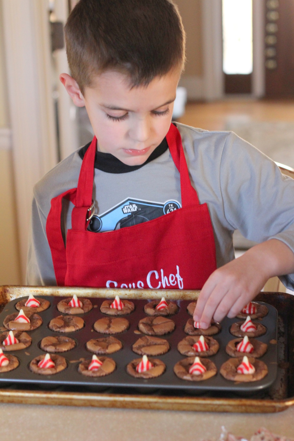 Boy putting pepperming candies on top of brownies in a tray