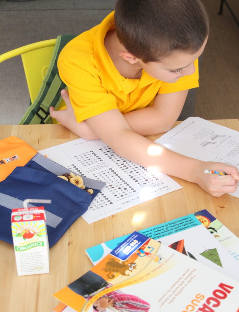 boy doing homework with juice box and scantron test booklet