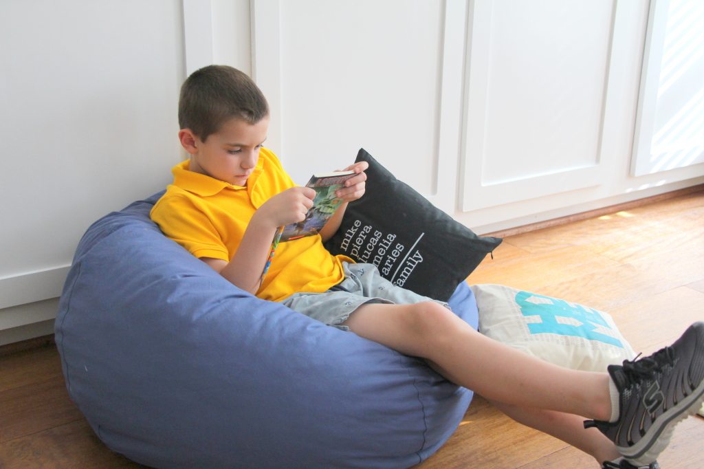 boy with book on bean bag chair