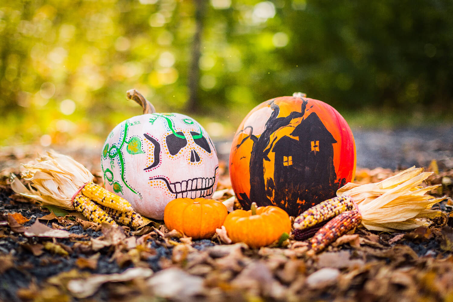 pumpkins with skull and haunted house painted on them