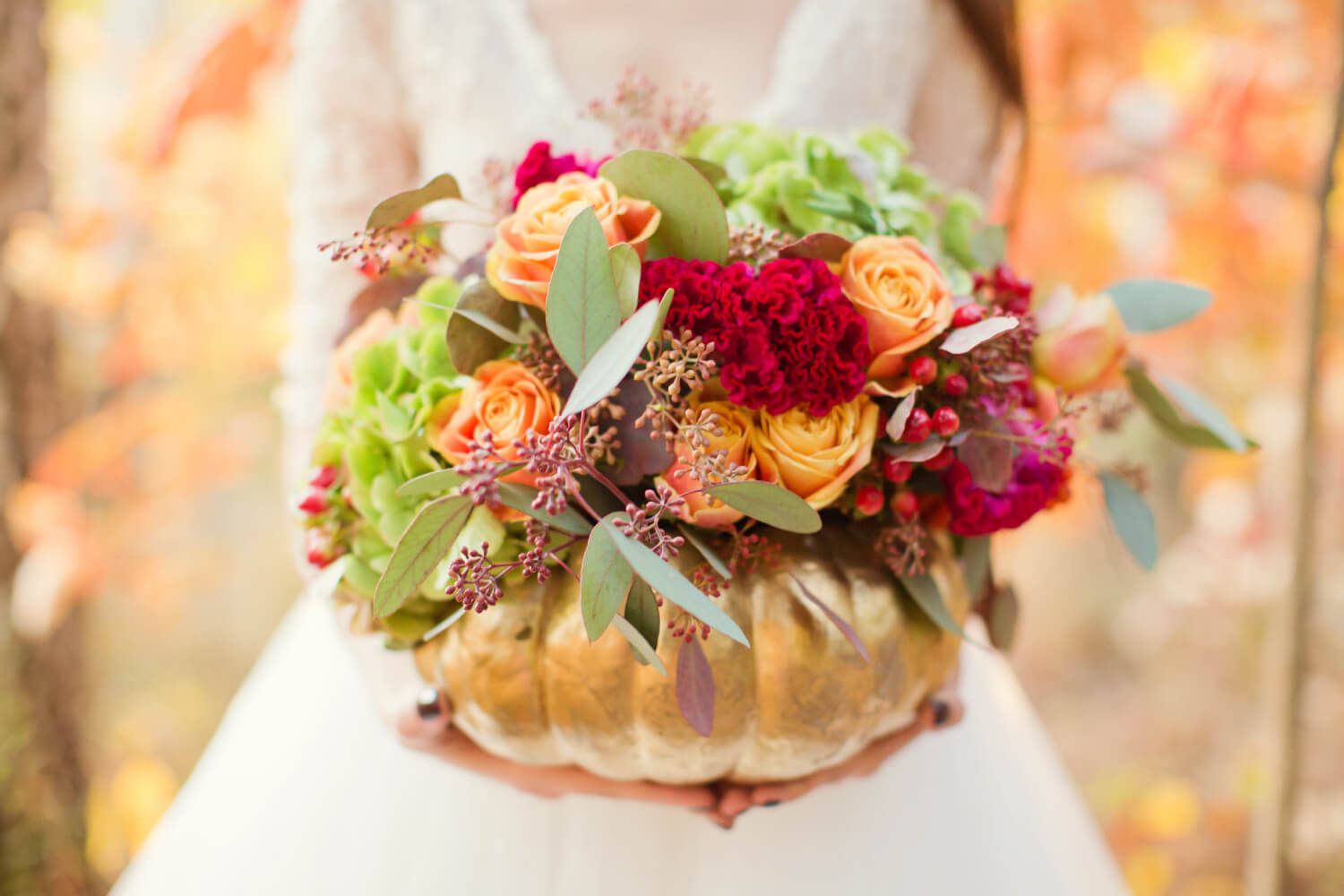 red and orange flowers in a gold pumpkin vase
