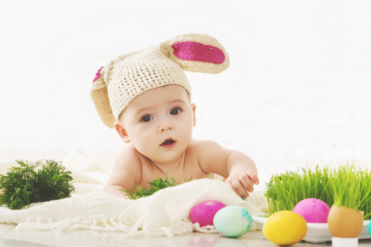 baby wearing knitted bunny ears with easter eggs