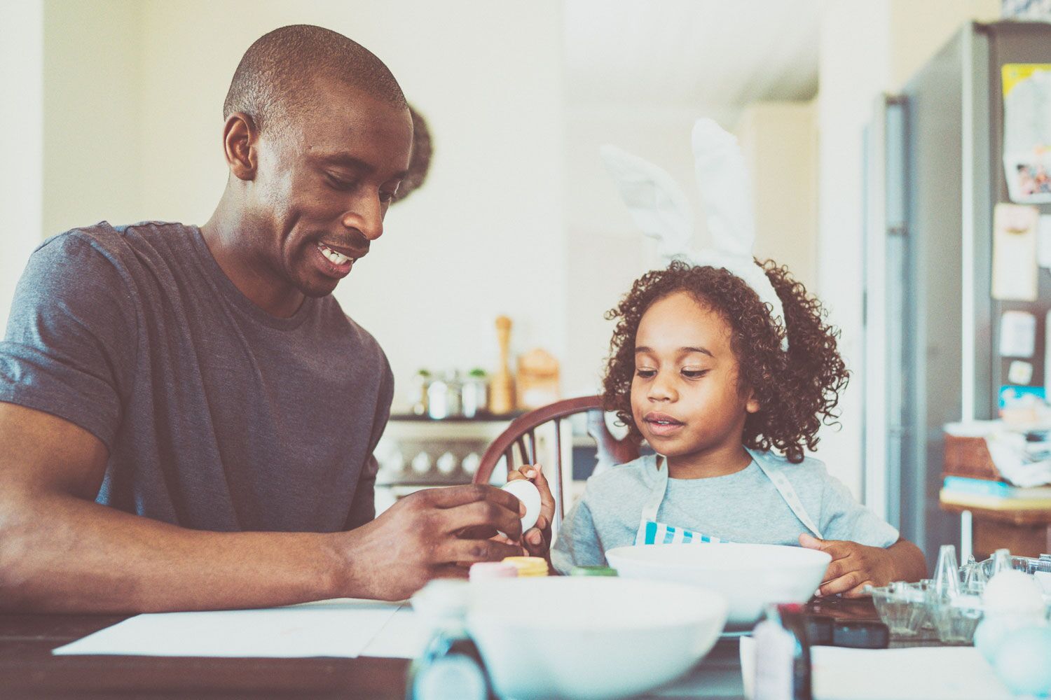 man and daughter with bunny ears making easter eggs