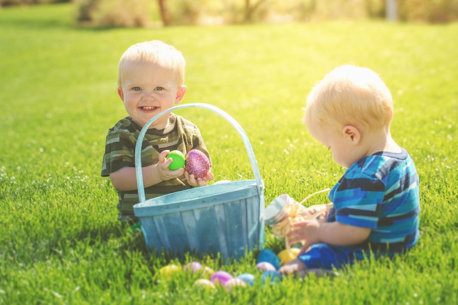 twin babies sitting in grass with easter basket